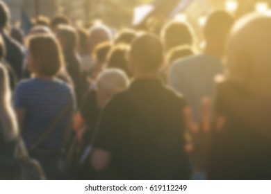 Defocused crowd attending political meeting, large group of of unrecognizable people as audience to politician's speech outdoors