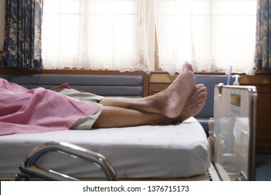 Defocused Feet Of Elderly Over 80 S Asian Man Patient Lie Down On Bed After Chemotherapy Of Liver Cancer In Hospital Ward Room, Senior Man Lie Down On Bed In Hospital Waiting The Doctor Examining.