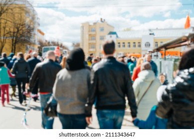 Defocused Group Of People Walking Down Street In City Center On Sunny Day Outdoors, Back View. Blurred Crowd Background, Rush Hour Abstract.