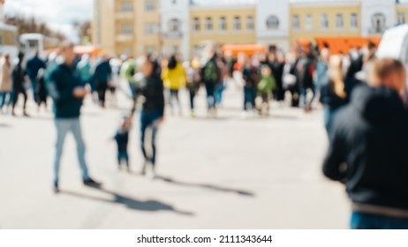 Defocused Group Of Unrecognizable People Walking Down Street In City Square On Sunny Day, Outdoors. Blurred Crowd Background, Rush Hour Abstract.