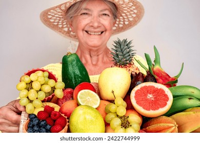 Defocused happy senior woman in straw hat holding basket full of fresh exotic fruit, healthy lifestyle concept - Powered by Shutterstock