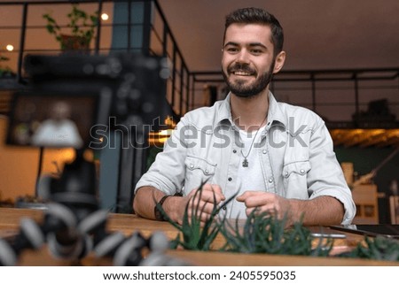 Defocused image of Caucasian video blogger vlogger broadcasting online using photo camera talking to subscribers clients customers. Personal blog for social media