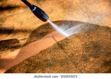 Defocused Image. Cleaning Backyard Paving Tiles Pathway With High Pressure Washer. Spring Clean Up