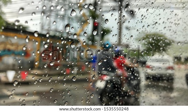 Defocused image, raindrop on car\
windshield,colorful bokeh with street light.Driving car in heavy\
rain storm.Traffic in the city on a rainy\
day.