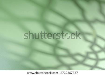 Defocused of Islamic shadow background with soft geometric mosque pattern on bright green surface. Suitable for Ramadan, Eid Mubarak, and Muslim greeting designs