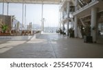 Defocused outdoor image with blurred background showcasing a spacious open walkway with modern architecture and distant silhouettes of people at a marina