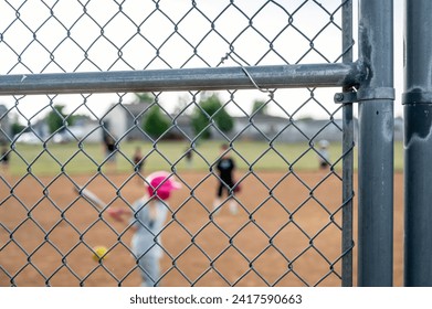 Defocused Parent view behind a chain link fence and home plate with a girl batter ready - Powered by Shutterstock