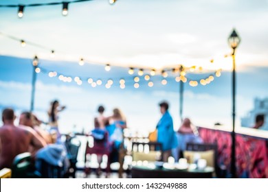 Defocused People Attending Open Air Summer Party On The Roof Top. Warm Sun Light In The Evening