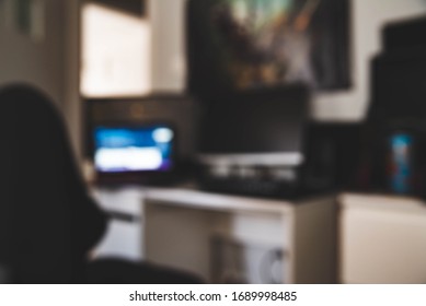 Defocused Photo Of Laptop, Backlit Pc Keyboard And Comfortable Chair. Working From Home. Home Office Background During Virus Pandemy