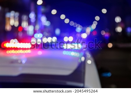 defocused photo of police car lights at night in city with selective focus and blurry car traffic in the bokeh