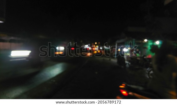 Defocused remote street nightlife: cars,\
motorcycles, street lights and small grocery shop\
