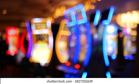 Defocused slot machines glow in casino on fabulous Las Vegas Strip, USA. Blurred gambling jackpot slots in hotel near Fremont street. Illuminated neon fruit machine for risk money playing and betting. - Shutterstock ID 1827332639