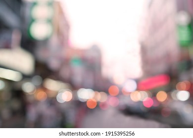 Defocused Street Light Photo, Blurry Road Building Car And People With Colourful Bokeh, Light Are Red White Pink And Orange.