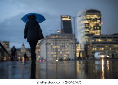 Defocused view of the City of London with a woman walking under the umbrella on a rainy day. Skyline includes 20 Fenchurch St and 122 Leadenhall St. - Powered by Shutterstock