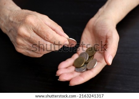 Defocused view to elderly woman counts metal coins, wrinkled female hands close up. Concept of poverty, pension payments, retiree with money