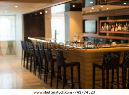 Defocused view of interior of an upmarket bar with stools surrounding the bar counter