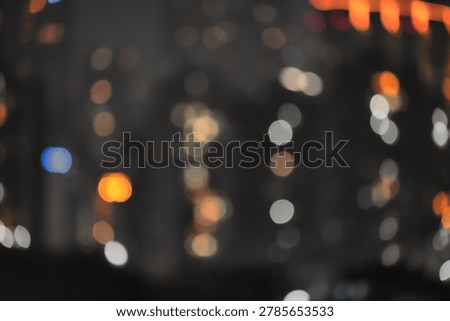 Defocused view of nighttime cityscape featuring illuminated buildings, glowing windows, and vibrant urban lights against the dark sky. Ideal for city life, architecture, business districts, tourism, and modern metropolitan themes.