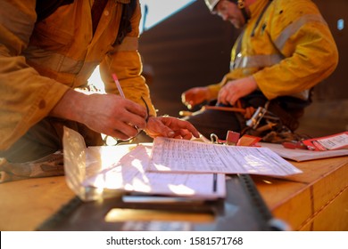 Defocused Worker Hand Checking On JHA Job Hazard Analysis Before Signing Hot Work Permit To Work On Isolation Safety Control Lock Box Prior To Work Defocused Senior Supervisor Seating Background