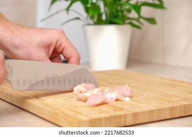 Defrosted Raw Chicken Fillet On Cutting Board. Slicing Fresh Raw Chicken Breast With Sharp Knife For Cooking Chopped Chicken Cutlets On A Bamboo Wooden Cutting Board For Slicing. Kitchen Knife Test.