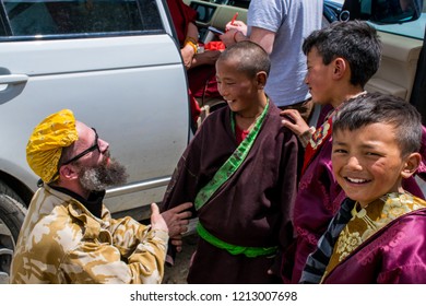 Dege County / China - May 2016: Tibetan boys ad European tourist on traditional festival near Buddhist Monastery in Eastern Tibet (Kham). Garze Tibetan Autonomous Prefecture, Sichuan.