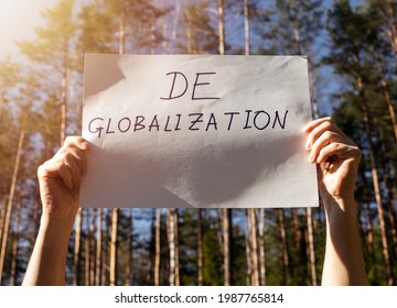 Deglobalization and reverse globalization concept. Word on paper poster in male hands with forest background.