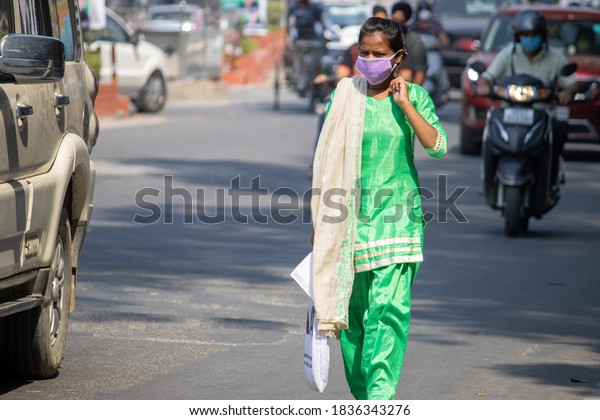 Dehradun, Uttarakhand/India-October 14 2020:A Young\
girl going on road wearing face mask, due to Corona pandemic in\
India, mask is mandatory in india due to pandemic. High quality\
photo