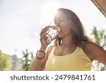 Dehydrated woman drinks clean water from a glass to replenish fluids during hot summer days.