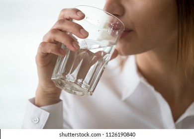 Dehydrated woman feeling thirsty holding glass drinking filtered pure mineral fresh water for body refreshment or energy recovery, dehydration problem, hydration and health concept, close up view