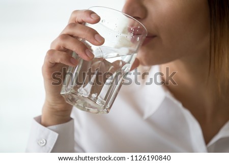 Dehydrated woman feeling thirsty holding glass drinking filtered pure mineral fresh water for body refreshment or energy recovery, dehydration problem, hydration and health concept, close up view