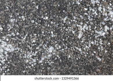 De-icing chemicals on the asphalt road. Pavement is sprinkled with technical salt or salt mixtures based on it, top view. Reagent - technical salt will make the road safe. 