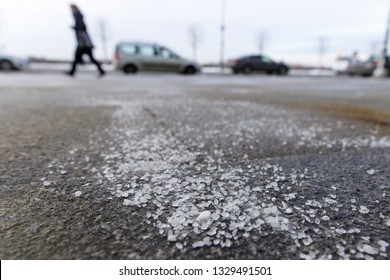 De-icing chemicals on the road. Pavement is sprinkled with technical salt or salt mixtures based on it, soft focus, blurred background. Reagent - technical salt will make the road safe. 