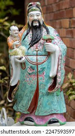 The deities are Fu.Fu is often portrayed as a man holding a Ru Yi (an emblem of power and authority) or a child, and is associated with good luck and fortune. - Shutterstock ID 2247593597