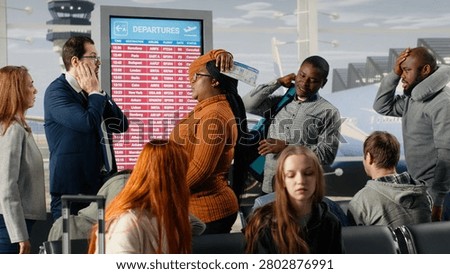 Dejected by plane being late, FIDS screen and upset men with women in airport checking departure time, tedious waiting, electronic timetable display announcement and passengers bummed by flight delay.