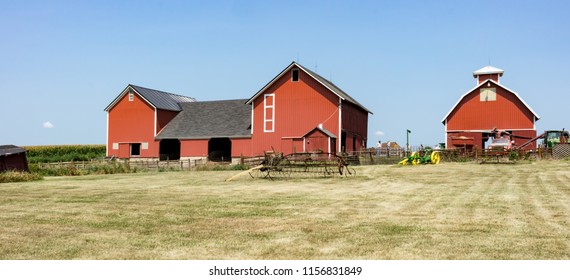 Dekalb County, Illinois / USA - August 11, 2018: A Traditional, Family Farm Displays Antique Farming Equipment During A Barn Tour. Bright Red, Old Barns And Corn Crib Stand Out Against Blue Sky.