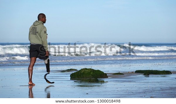 Del Mar, CA / USA - January 27, 2019: A man\
(likely an injured veteran) with a Flex-Foot prosthesis walks on\
the beach                               \
