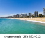 Viña del Mar sandy beach with High-Rise Buildings and Turquoise Ocean. Vacation destination for relaxing at the pacific sea. Viewpoint of coastal city with skyline in the background.