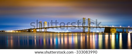 Delaware Memorial Bridge by night, viewed from New Jersey. The Delaware Memorial Bridge is a set of twin suspension bridges crossing the Delaware River between the states of Delaware and New Jersey