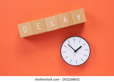 Delay; Five wooden blocks with "DELAY" text of concept and a simple clock.