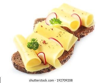 Delcious Rolled Slices Of Golden Gouda Cheese On A Wholewheat Sandwich Garnished With Sliced Radish And Parsley On A White Background