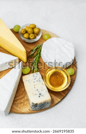 Delectable cheese platter with assorted cheeses, olives, honey, and grapes.