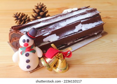 Delectable Chocolate Yule Log Cake with Blurry Dried Pine Cone and Christmas Decorations - Shutterstock ID 2236110117