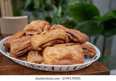 A delectable display of assorted pastries piled on a white platter, set against a lush green background, showcasing the delightful presentation of baked goods.