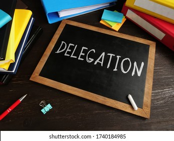 Delegation written in chalk on a blackboard. Delegating concept.