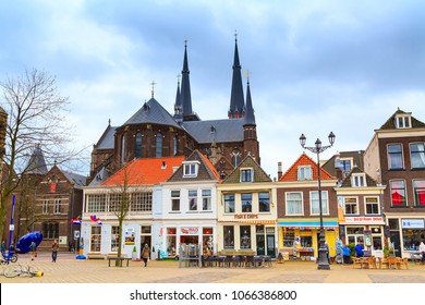 Delft, Netherlands - April 8, 2016: Colorful street view with traditional dutch houses, cathedral, bicycles, people in downtown of popular Holland destination