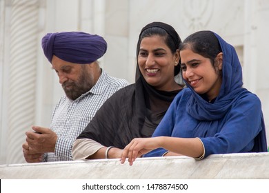 Delhi, India; 03 march 2017: 
Sikh women watching from a balcony with a man in the background, in one of the hallways of the Gurdwara Bangla Sahib temple