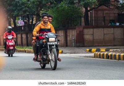 Delhi, India - 03/07/2020: Three people commuting on a bike for fun violating traffic rules and lockdown curfew during Covid 19 outbreak. Indian biker without helmet risking his health and safety.
