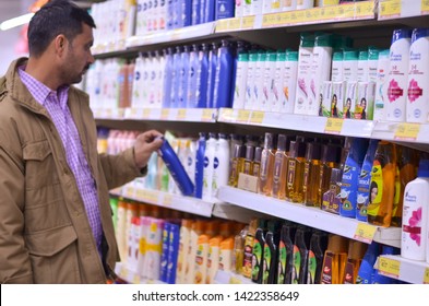 Delhi, India, 2020. Man Browsing Through Shampoo, Hair Oil And Face Wash Bottles On Display At The Aisle In Rows In A Supermarket Departmental Store In A Mall.