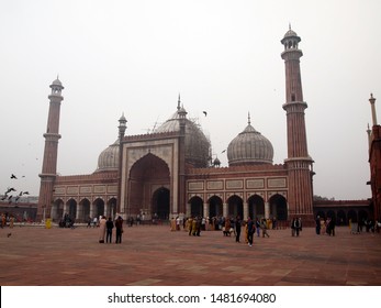 Delhi / India - February, 2nd, 2019: courtyard of Jama Masjid mosque on an overcast day with fog and smog (air pollution).  People sightseeing Moghul architecture, very white sky with low visibility.