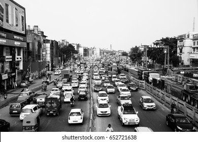 DELHI, INDIA - JULY 5, 2016: Heavy car traffic in the city center of Delhi, India. Buses and construction nearby the road. Various shops, cafes, restaurants. Black and white