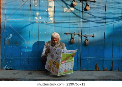 Delhi, India March 2022: A Man Reading Sunday Hindi Newspaper In Front Of Closed Shop.